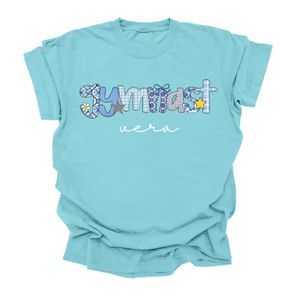 A mint color t-shirt with a personalized name printed on the front, featuring a patterned 'Gymnast' design with various gymnastics icons like a balance beam and stars.